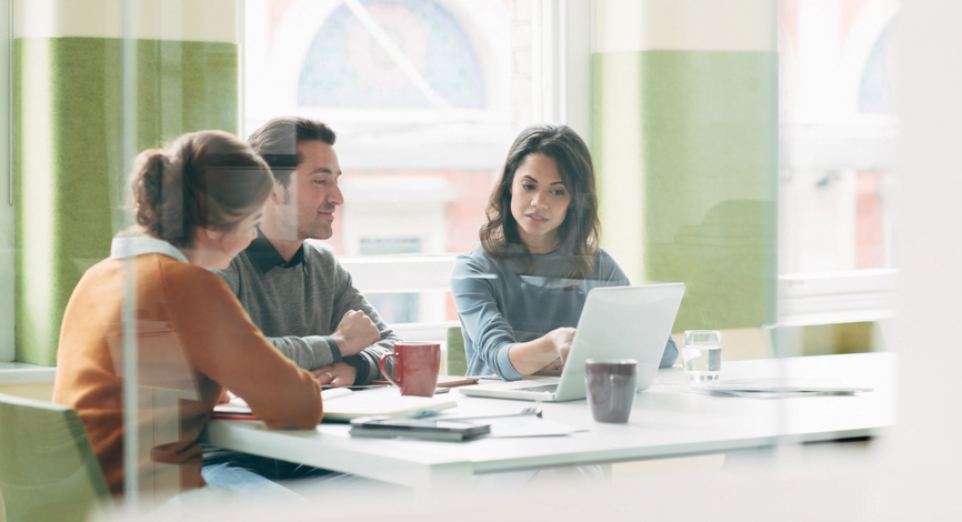 three people in a meeting around one computer